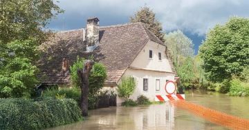 Zatopený dům po povodni s výstražnou značkou – riziko živelných katastrof u rekreačních nemovitostí